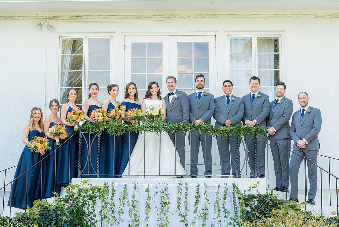 Bridal party dressed in navy blue bridesmaids gowns and grey suits for a fall wedding in upstate New York, just outside NYC, in Chappaqua, Westchester County. The wedding at Crabtree's Kittle House had an outdoor ceremony then reception indoors. It was filled with pumpkins, autumn leaves, orange, white, and peach colors. Photos taken by Mikkel Paige Photography. #mikkelpaige #fallwedding #newyorkweddingvenues #nycweddingphotographer #outdoorceremony #navybluebridesmaids #autumnwedding