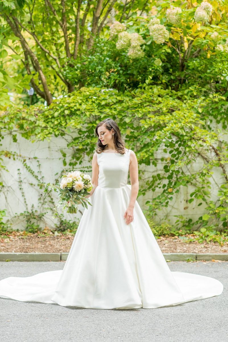 Photographs were taken by Mikkel Paige Photography for a fall wedding in upstate New York, just outside NYC, in Chappaqua, Westchester County. The bride wore a long silk gown with a bow on the back for her Crabtree's Kittle House celebration outdoors. It was filled with pumpkins, autumn leaves, orange, white, peach and navy colors. The bride's gown had a long train and back bow. #mikkelpaige #fallwedding #newyorkweddingvenues #BrideStyle #autumnbouquet #glambride #elegantbride