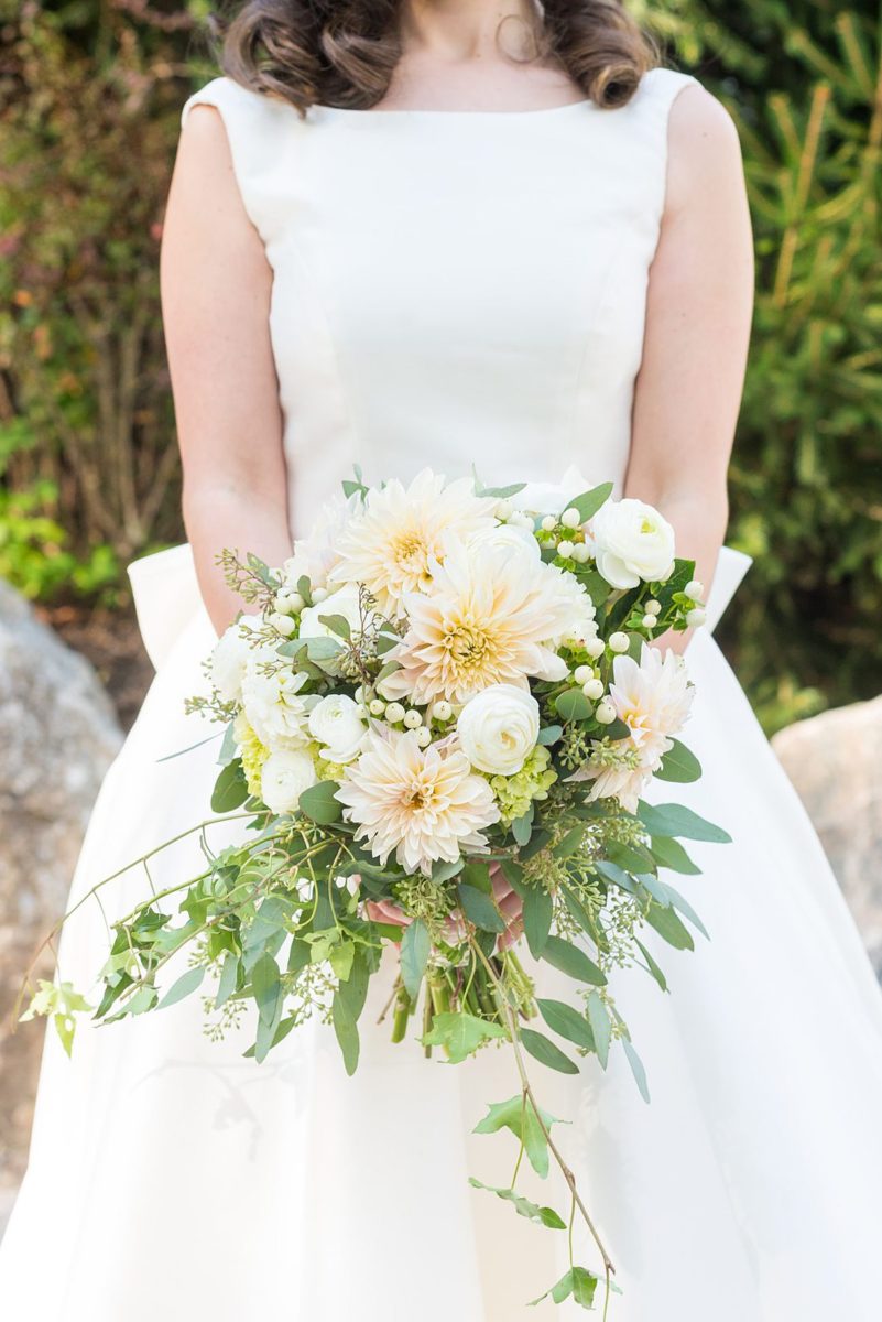 Bride dressed in a white gown with long train for her fall wedding in upstate New York, just outside NYC, in Chappaqua, Westchester County. The wedding at Crabtree's Kittle House had an outdoor ceremony then reception indoors. It was filled with pumpkins, autumn leaves, orange, white, and peach colors. Bouquet photo taken by Mikkel Paige Photography with ivy and dahlias. #mikkelpaige #fallwedding #newyorkweddingvenues #nycweddingphotographer #bridestyle #autumnwedding #fallbouquet