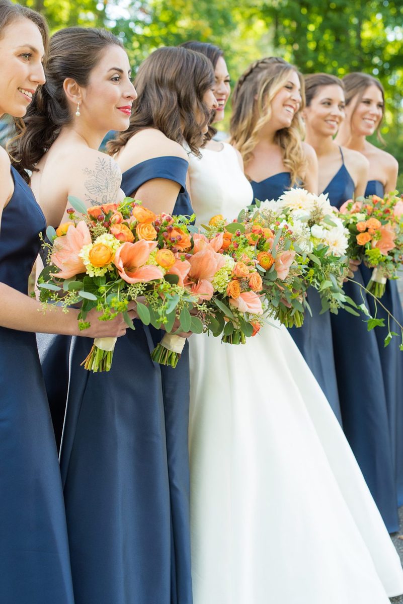 Bride dressed in a white gown with long train for her fall wedding in upstate New York, just outside NYC, in Chappaqua, Westchester County. The wedding at Crabtree's Kittle House had an outdoor ceremony then reception indoors. It was filled with pumpkins, autumn leaves, orange, white, and peach colors. Bouquet photo by Mikkel Paige Photography with dahlias + amaryllis. #mikkelpaige #fallwedding #newyorkweddingvenues #nycweddingphotographer #bridestyle #autumnwedding #fallbouquets #bridesmaids