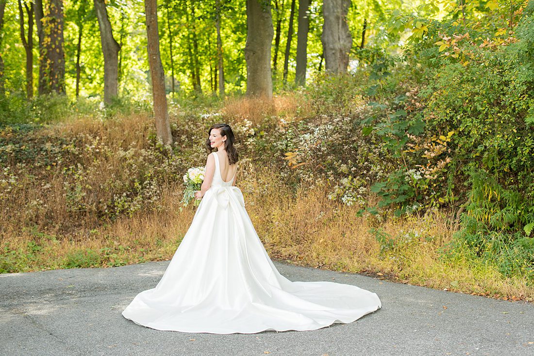 Photographs were taken by Mikkel Paige Photography for a fall wedding in upstate New York, just outside NYC, in Chappaqua, Westchester County. The bride wore a long silk gown with a bow on the back for her Crabtree's Kittle House celebration outdoors. It was filled with pumpkins, autumn leaves, orange, white, peach and navy colors. The bride's gown had a long train and back bow. #mikkelpaige #fallwedding #newyorkweddingvenues #BrideStyle #autumnbouquet #glambride #elegantbride