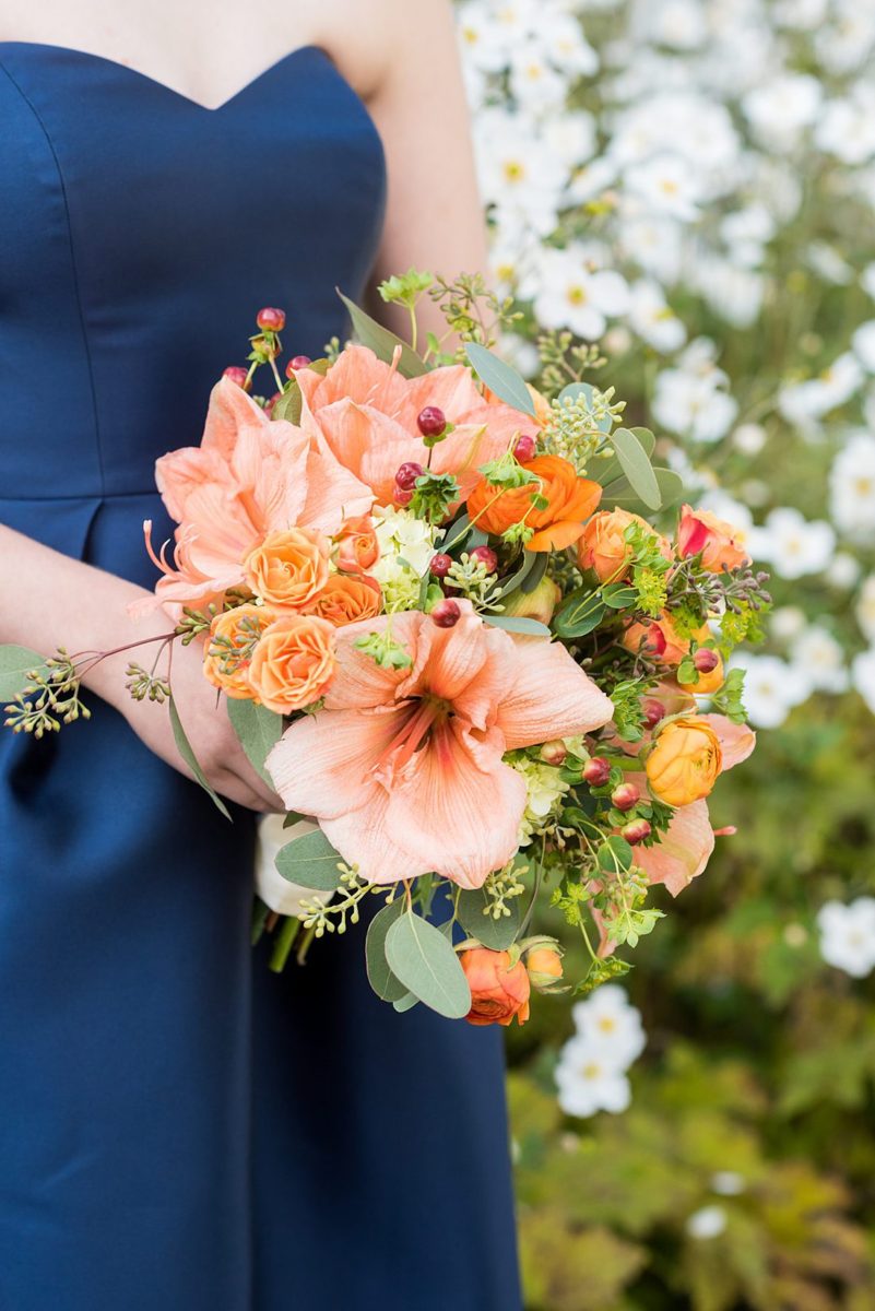 Bridesmaid in a navy dress for a fall wedding in upstate New York, just outside NYC, in Chappaqua, Westchester County. The wedding at Crabtree's Kittle House had an outdoor ceremony then reception indoors. It was filled with pumpkins, autumn leaves, orange, white, and peach colors. Bouquet photo by Mikkel Paige Photography with dahlias + amaryllis. #mikkelpaige #fallwedding #newyorkweddingvenues #nycweddingphotographer #bridestyle #autumnwedding #fallbouquets #bridesmaids