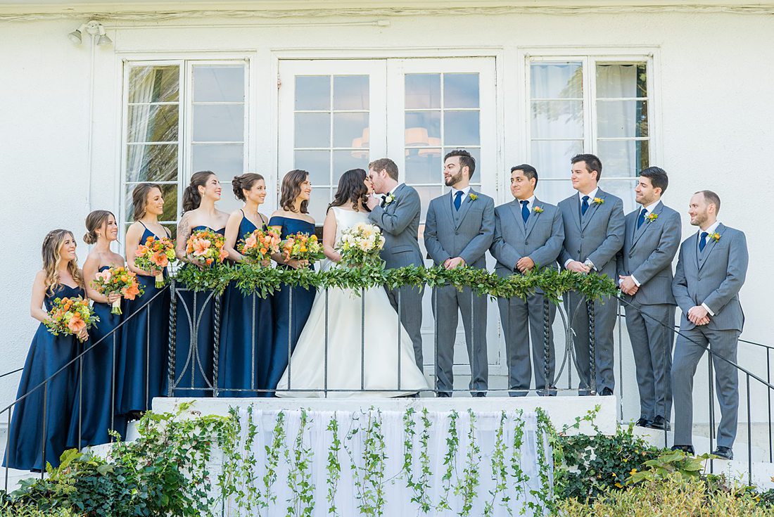 Bridal party dressed in navy blue bridesmaids gowns and grey suits for a fall wedding in upstate New York, just outside NYC, in Chappaqua, Westchester County. The wedding at Crabtree's Kittle House had an outdoor ceremony then reception indoors. It was filled with pumpkins, autumn leaves, orange, white, and peach colors. Photos taken by Mikkel Paige Photography. #mikkelpaige #fallwedding #newyorkweddingvenues #nycweddingphotographer #outdoorceremony #navybluebridesmaids #autumnwedding