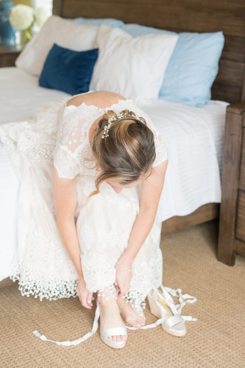 A detail picture of the bride putting her white wedge heels on that she wore for her wedding day and reception on a tented lawn. Their Saratoga Springs destination wedding photos in upstate New York are by Mikkel Paige Photography, NY wedding photographer. #mikkelpaige #saratogaspringswedding #destinationwedding #bridalparty #bohobride #wedges #bridalshoes #bridestyle