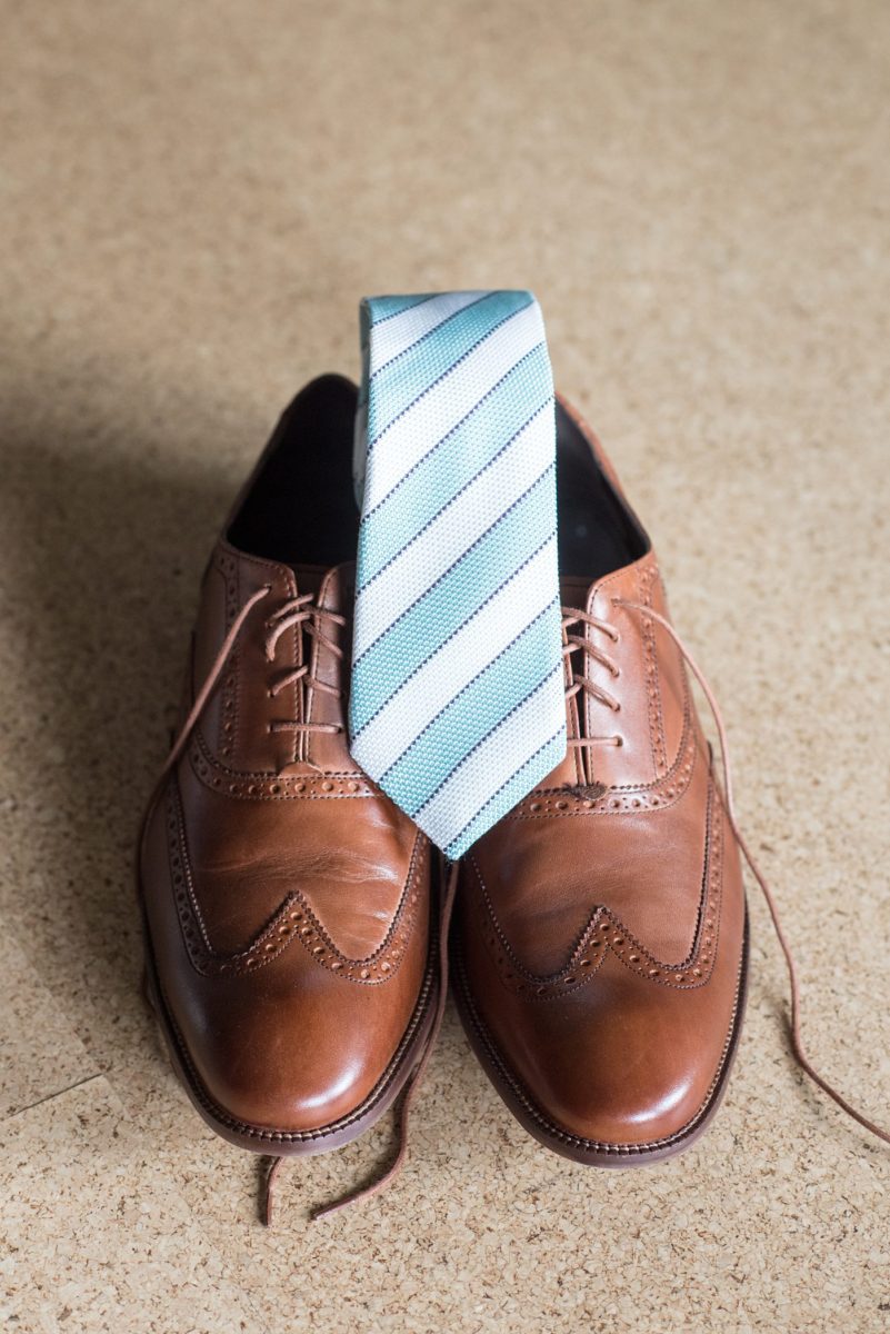 Pictures of the groom getting ready and putting on his brown leather shoes as he was getting ready for his wedding day. Their Saratoga Springs destination wedding photos in upstate New York are by Mikkel Paige Photography, NY wedding photographer. #mikkelpaige #saratogaspringswedding #destinationwedding #groomstyle #groomshoes #stripedtie