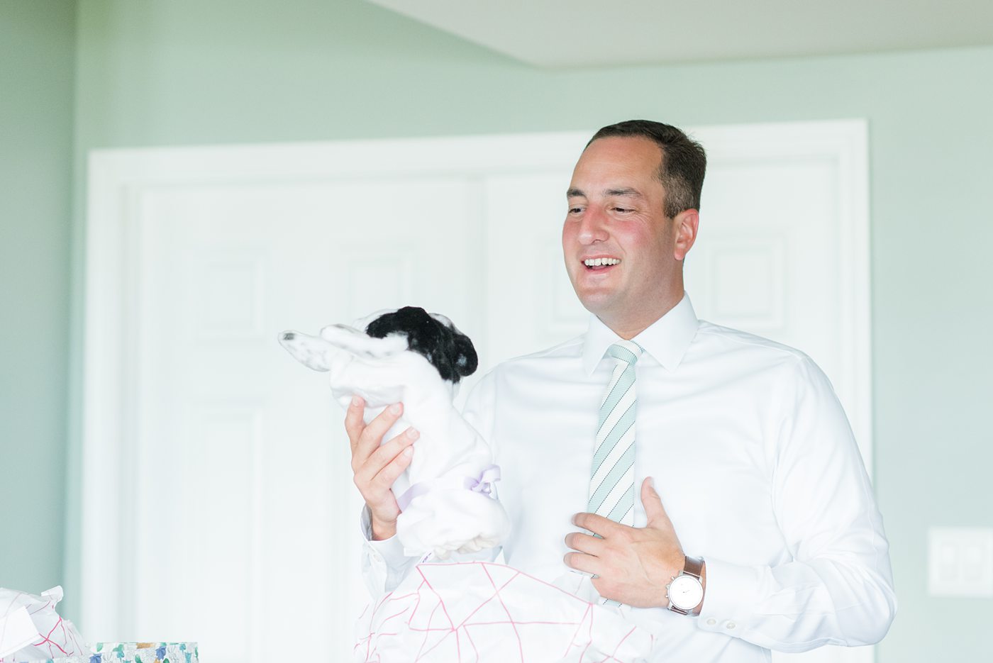 Pictures of the groom getting ready and opening his unique golf-cover gift, customized to look like the bride and groom's dog, on their their wedding day. Their Saratoga Springs destination wedding photos in upstate New York are by Mikkel Paige Photography, NY wedding photographer. #mikkelpaige #saratogaspringswedding #destinationwedding #groomgift #golfcover