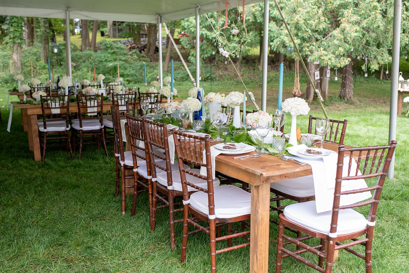Saratoga Springs destination wedding photos in upstate New York by Mikkel Paige Photography, NY wedding photographer. The bride and groom tented a lawn for their reception. They had wood Chiavari chairs, milk glass and vintage salt and pepper shakers on each table. The table numbers were destinations the couple had been. #mikkelpaige #saratogaspringswedding #destinationwedding #lakefrontwedding #waterfrontwedding #lakewedding #tablenumbers #weddingreception #intimatewedding
