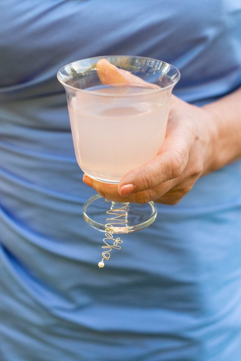 Saratoga Springs destination wedding photos in upstate New York by Mikkel Paige Photography, NY wedding photographer. The bride and groom tented a lawn for their reception and custom bar with wire wine glass charms for each guest. Their name was wrapped in gold or written on a wood disc. #mikkelpaige #saratogaspringswedding #destinationwedding #lakefrontwedding #waterfrontwedding #lakewedding #custombar #winecharms #weddingdetails