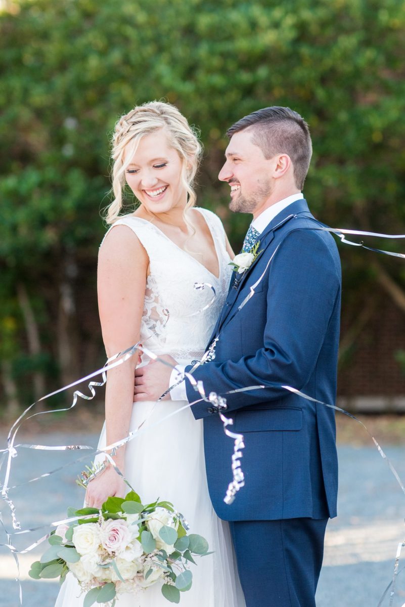 Chatham Station wedding photos my Mikkel Paige Photography from this urban chic beautiful venue in Cary, North Carolina. Picture of the bride in a white tulle gown and groom in a blue suit with silver confetti. #mikkelpaige #RaleighWeddingphotographer #chathamstation #CaryNC #weddingvenues #brideandgroom