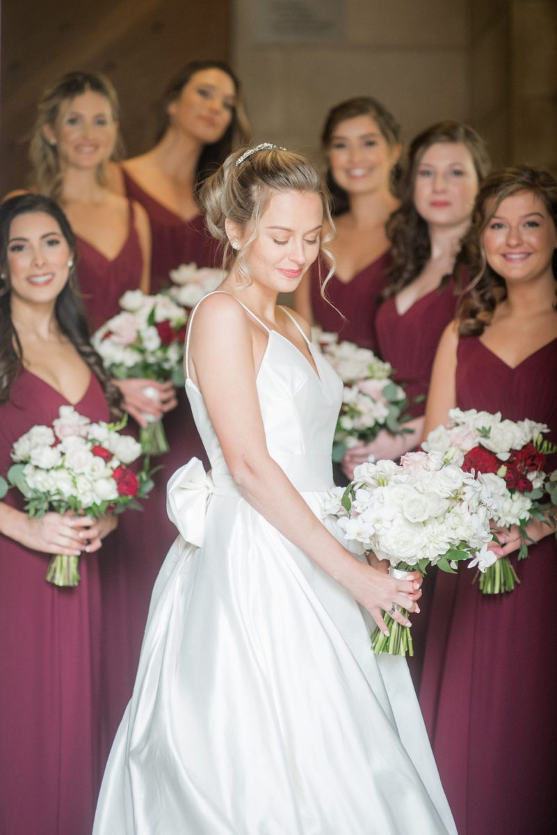 Photo of a bride and her bridesmaids in maroon gowns at Duke Chapel, in Durham North Carolina, by Mikkel Paige Photography. #mikkelpaige #dukechapel #DukeWedding #durhamweddingphotographer #redbridesmaidsgowns #novemberwedding