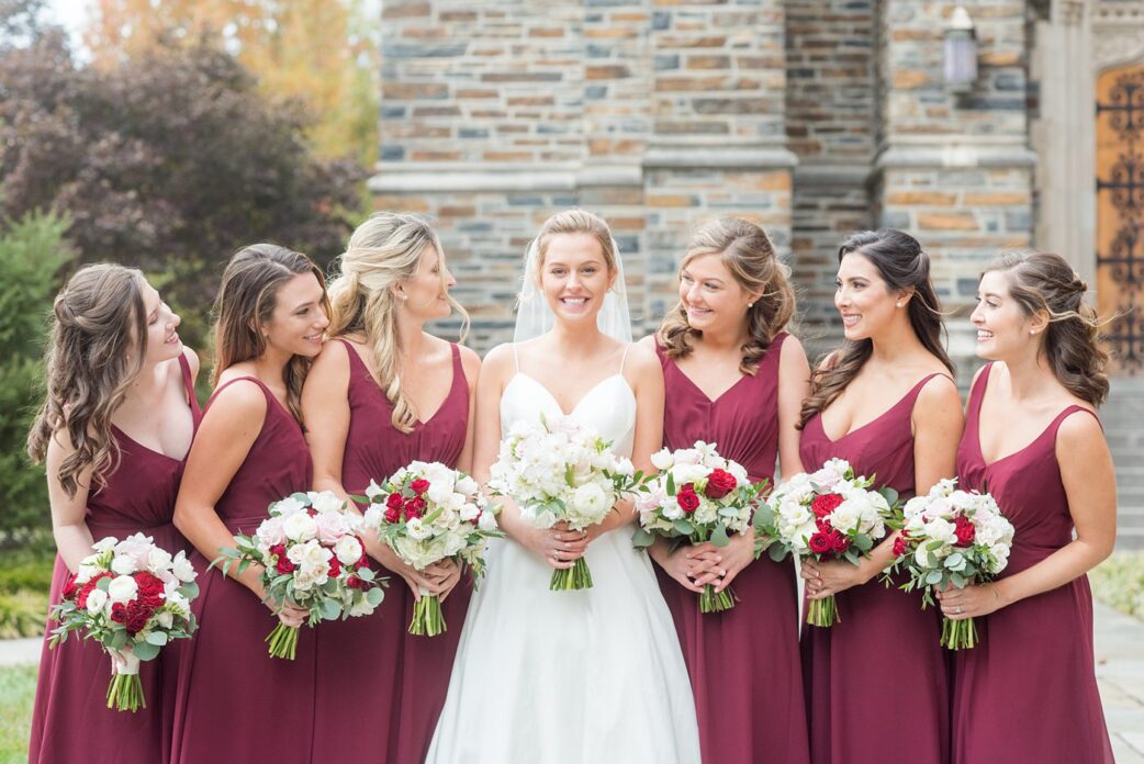 Photo of a bride and her bridesmaids in maroon gowns at Duke Chapel, in Durham North Carolina, by Mikkel Paige Photography. #mikkelpaige #dukechapel #DukeWedding #durhamweddingphotographer #redbridesmaidsgowns #novemberwedding