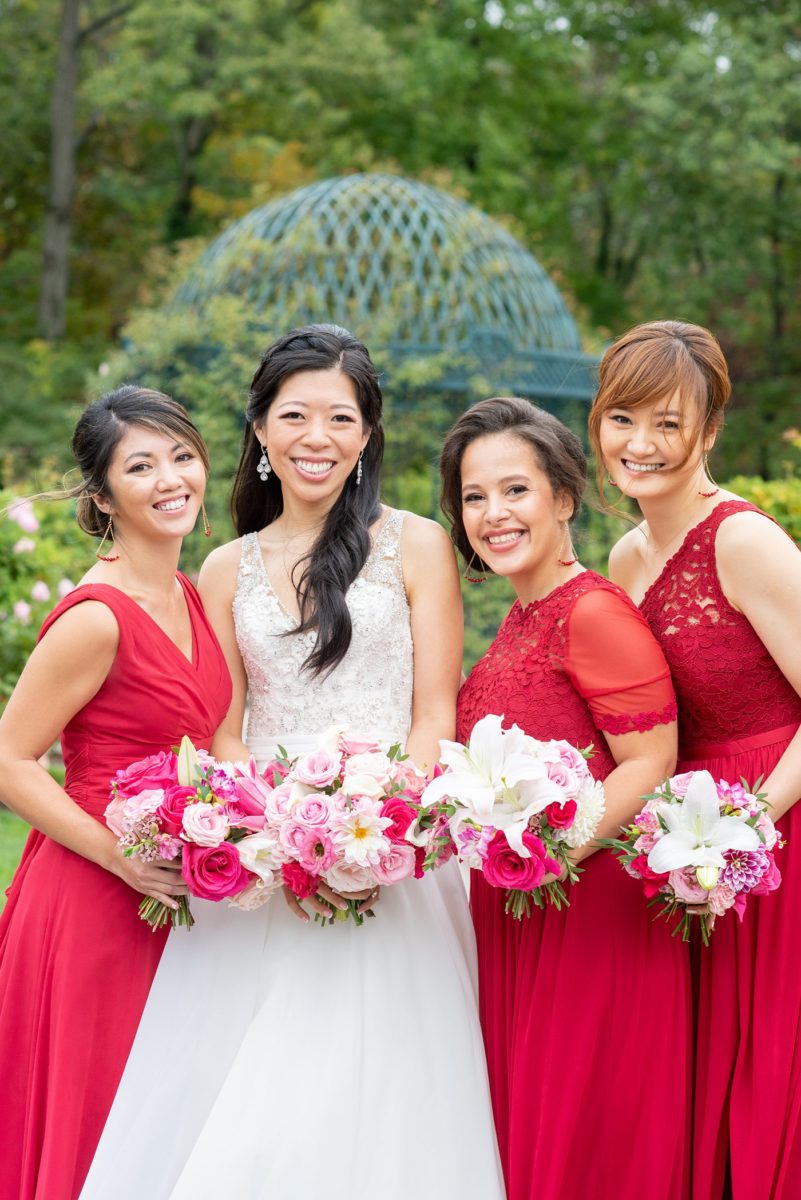 New York Botanical Garden wedding photos with bridesmaids in red gowns and the bride in a beaded bodice and ballgown with long train, by Mikkel Paige Photography. After the couple's engagement photoshoot in Manhattan I was so excited for their fall wedding near the Conservatory at the Terrace Room, at this NYC venue. #mikkelpaige #nybg #newyorkbotanicalgardenwedding #asianbride #NYBotanicalGarden #Bronxwedding #newyorkcityweddingvenues #bridestyle #weddingparty #redbridesmaids #bridalparty