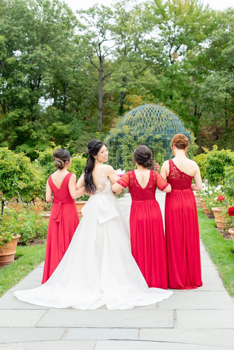 New York Botanical Garden wedding photos with bridesmaids in red gowns and the bride in a beaded bodice and ballgown with long train, by Mikkel Paige Photography. After the couple's engagement photoshoot in Manhattan I was so excited for their fall wedding near the Conservatory at the Terrace Room, at this NYC venue. #mikkelpaige #nybg #newyorkbotanicalgardenwedding #asianbride #NYBotanicalGarden #Bronxwedding #newyorkcityweddingvenues #bridestyle #weddingparty #redbridesmaids #bridalparty