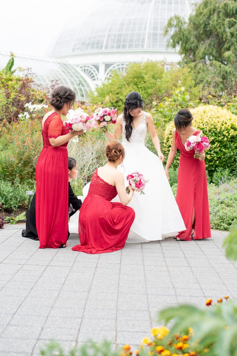 New York Botanical Garden wedding photos with bridesmaids in red gowns and the bride in a beaded bodice and ballgown with long train, by Mikkel Paige Photography. After the couple's engagement photoshoot in Manhattan I was so excited for their fall wedding near the Conservatory at the Terrace Room, at this NYC venue. #mikkelpaige #nybg #newyorkbotanicalgardenwedding #asianbride #NYBotanicalGarden #Bronxwedding #newyorkcityweddingvenues #bridestyle #weddingparty #redbridesmaids #bridalparty