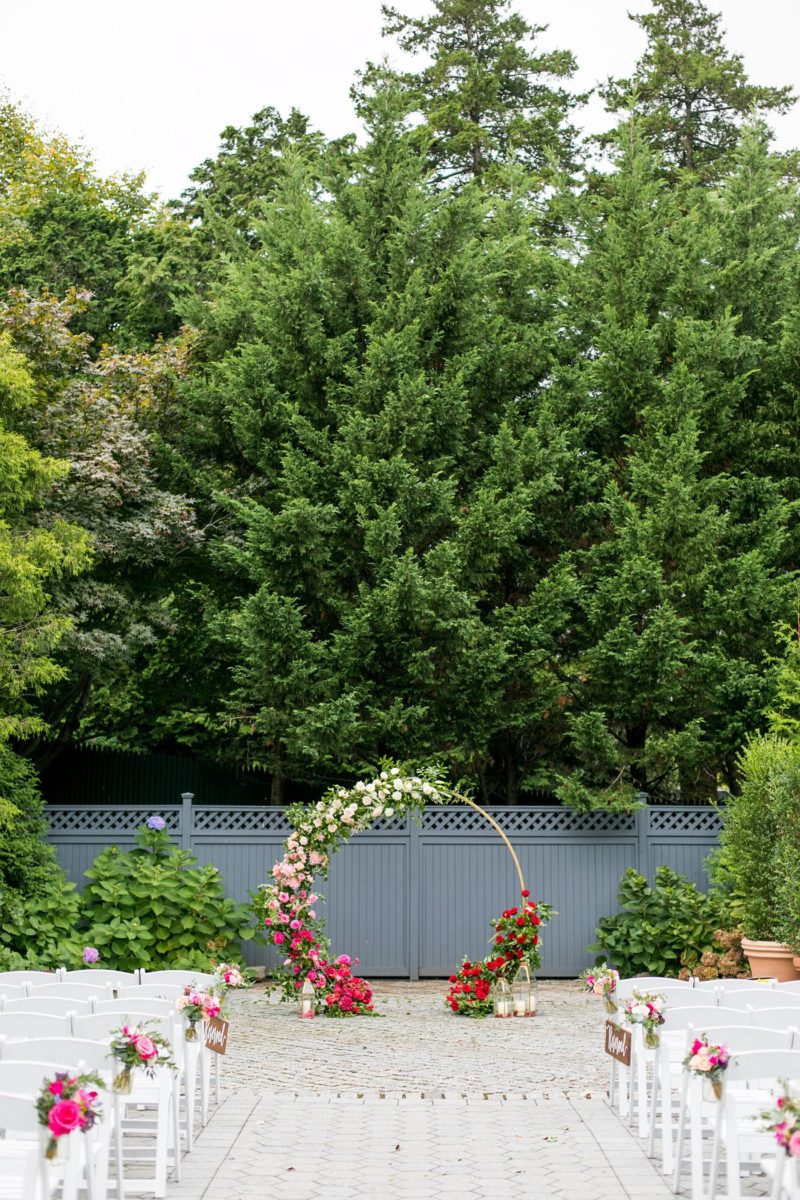 Outdoor ceremony at a New York Botanical Garden wedding photos by Mikkel Paige Photography. After the couple's engagement photoshoot in Manhattan I was so excited for their fall wedding near the Conservatory at the Terrace Room, at this NYC venue. Their backdrop was an ombre flower circle with pink and red blooms. #mikkelpaige #nybg #newyorkbotanicalgardenwedding #asianbride #NYBotanicalGarden #Bronxwedding #newyorkcityweddingvenues #weddingceremony #ombreflowers