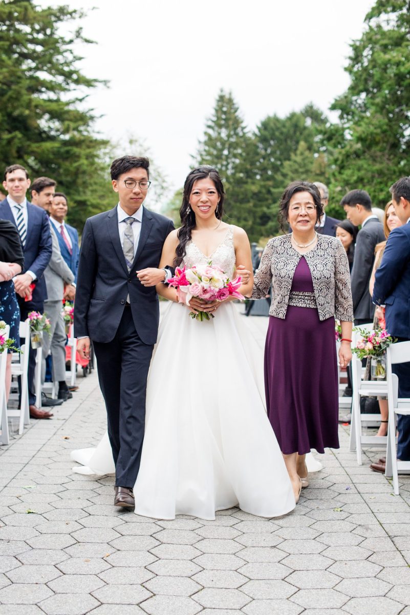 Outdoor ceremony at a New York Botanical Garden wedding photos by Mikkel Paige Photography. After the couple's engagement photoshoot in Manhattan I was so excited for their fall wedding near the Conservatory at the Terrace Room, at this NYC venue. Their backdrop was an ombre flower circle with pink and red blooms. #mikkelpaige #nybg #newyorkbotanicalgardenwedding #asianbride #NYBotanicalGarden #Bronxwedding #newyorkcityweddingvenues #weddingceremony #ombreflowers