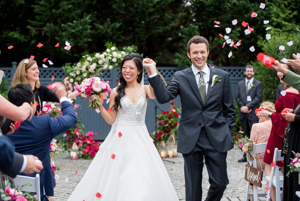 Outdoor ceremony at a New York Botanical Garden wedding photos by Mikkel Paige Photography. After the couple's engagement photoshoot in Manhattan I was so excited for their fall wedding near the Conservatory at the Terrace Room, at this NYC venue. Their backdrop was an ombre flower circle with pink and red blooms. #mikkelpaige #nybg #newyorkbotanicalgardenwedding #asianbride #NYBotanicalGarden #Bronxwedding #newyorkcityweddingvenues #weddingceremony #ombreflowers #tietheknot