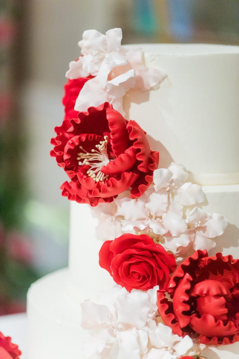 New York Botanical Garden wedding photos by Mikkel Paige Photography with an outdoor ceremony and indoor reception at the Terrace Room. After the couple's engagement photoshoot in Manhattan I was excited for their fall wedding near the Conservatory, at this NYC venue. The bride and groom cut their white fondant cake with red and pink gumpaste flowers. #mikkelpaige #nybg #newyorkbotanicalgardenwedding #NYBotanicalGarden #Bronxwedding #newyorkcityweddingvenues #weddingcake #gumpasteflowers 