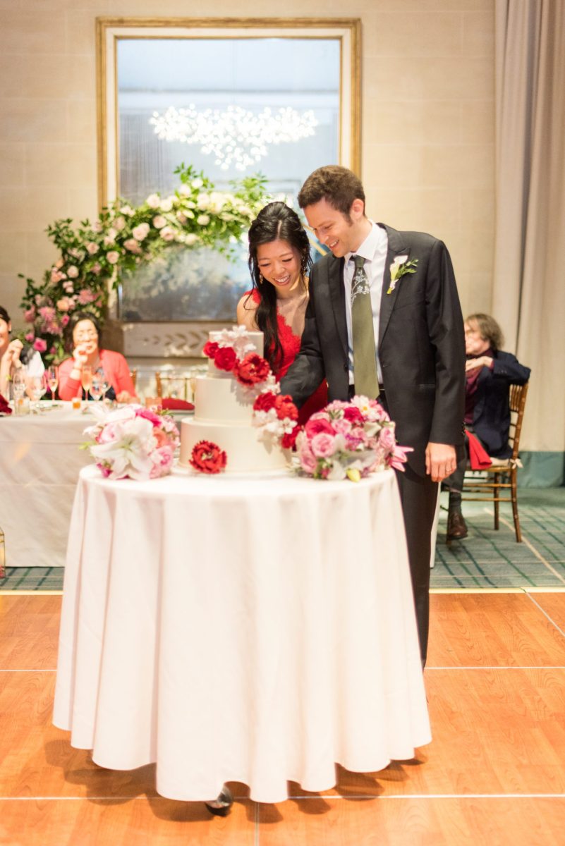 New York Botanical Garden wedding photos by Mikkel Paige Photography with an outdoor ceremony and indoor reception at the Terrace Room. After the couple's engagement photoshoot in Manhattan I was excited for their fall wedding near the Conservatory, at this NYC venue. The bride and groom cut their white fondant cake with red and pink gumpaste flowers. #mikkelpaige #nybg #newyorkbotanicalgardenwedding #NYBotanicalGarden #Bronxwedding #newyorkcityweddingvenues #weddingcake #gumpasteflowers