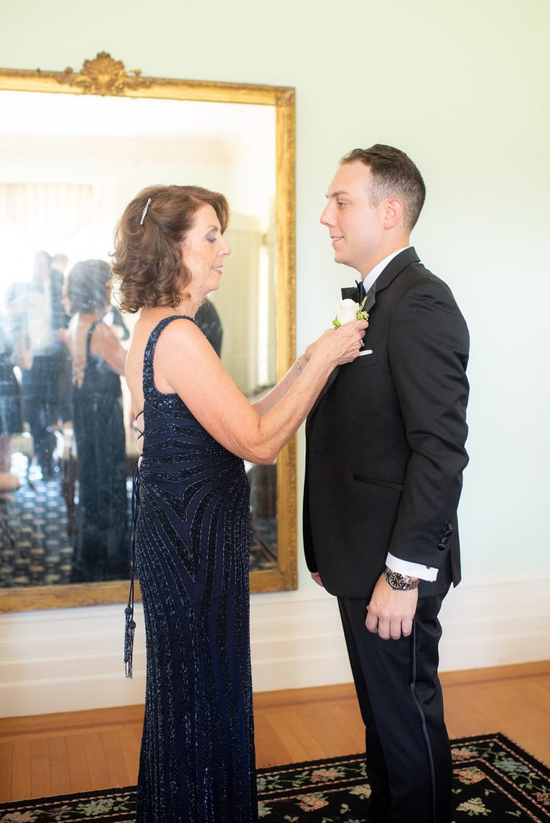 Photos by Mikkel Paige Photography at Waveny House wedding venue in New Canaan, Connecticut. This beautiful venue has an outdoor garden for the ceremony and indoor room for reception. The groom got ready for his wedding with a boutonniere pinning by his mother in the historic house. #mikkelpaige #wavenyhouse #wavenyhousewedding #connecticutweddingvenue #connecticutweddingphotographer #motherofthegroom #gettingready #groomstyle