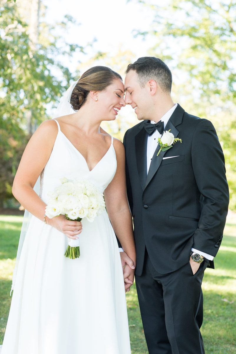 Photos by Mikkel Paige Photography at Waveny House wedding venue in New Canaan, Connecticut. This beautiful venue has an outdoor garden for the ceremony and indoor historic home for the reception. The bride and groom took photos on the park property, him in a tuxedo and her in a simple white gown with elaborate lace back. She carried an all white and ivory bouquet. #mikkelpaige #wavenyhouse #wavenyhousewedding #connecticutweddingvenue #connecticutweddingphotographer #brideandgroom #whitebouquet