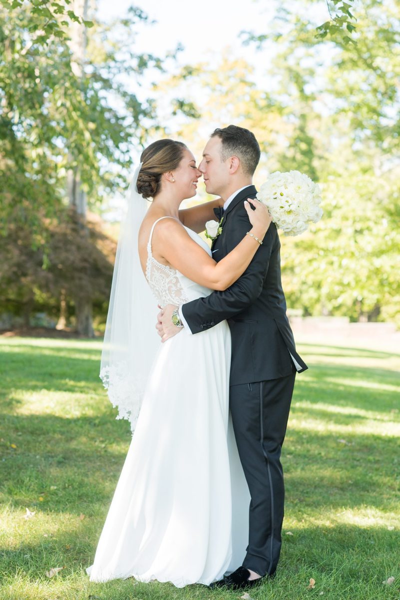 Photos by Mikkel Paige Photography at Waveny House wedding venue in New Canaan, Connecticut. This beautiful venue has an outdoor garden for the ceremony and indoor historic home for the reception. The bride and groom took photos on the park property, him in a tuxedo and her in a simple white gown with elaborate lace back. She carried an all white and ivory bouquet. #mikkelpaige #wavenyhouse #wavenyhousewedding #connecticutweddingvenue #connecticutweddingphotographer #brideandgroom #whitebouquet