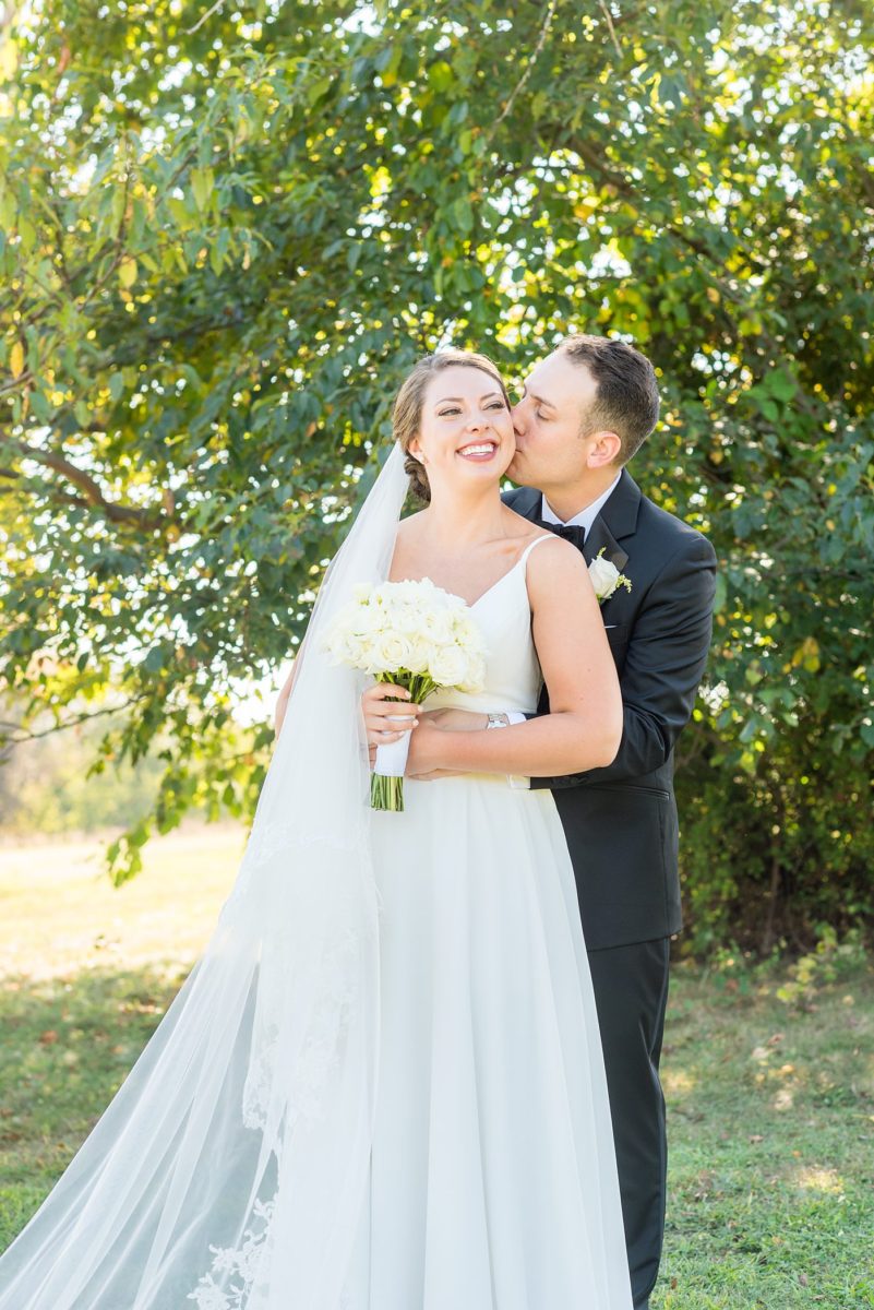 Photos by Mikkel Paige Photography at Waveny House wedding venue in New Canaan, Connecticut. This beautiful venue has an outdoor garden for the ceremony and indoor historic home for the reception. The bride and groom took photos on the park property, him in a tuxedo and her in a simple white gown with elaborate lace back. She carried an all white and ivory bouquet. #mikkelpaige #wavenyhouse #wavenyhousewedding #connecticutweddingvenue #connecticutweddingphotographer #brideandgroom #whitebouquet