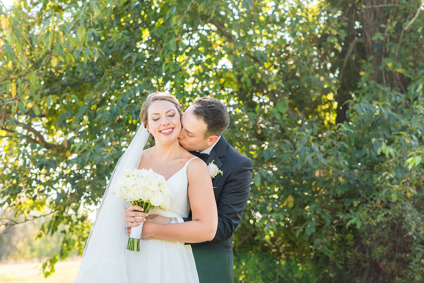 Photos by Mikkel Paige Photography at Waveny House wedding venue in New Canaan, Connecticut. This beautiful venue has an outdoor garden for the ceremony and indoor historic home for the reception. The bride and groom took photos on the park property, him in a tuxedo and her in a simple white gown with elaborate lace back. She carried an all white and ivory bouquet. #mikkelpaige #wavenyhouse #wavenyhousewedding #connecticutweddingvenue #connecticutweddingphotographer #brideandgroom #whitebouquet