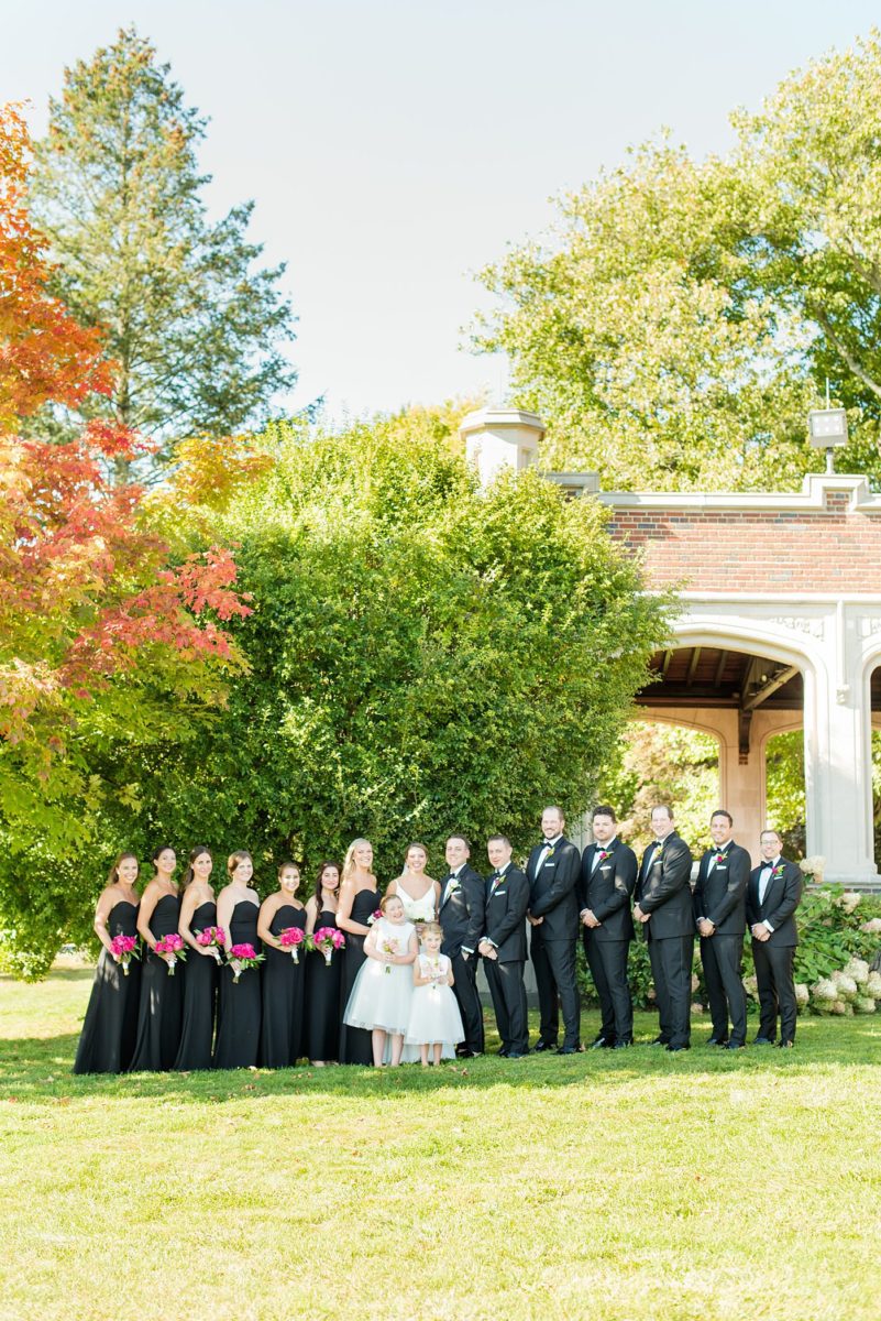 Photos by Mikkel Paige Photography at Waveny House wedding venue in New Canaan, Connecticut. This beautiful venue has an outdoor garden for the ceremony and indoor historic home for the reception. The bride wore an elegant, simple white gown and bridesmaids wore black dresses with hot pink bouquets. The groomsmen wore black tuxedos with rose boutonnieres. #mikkelpaige #wavenyhouse #wavenyhousewedding #connecticutweddingvenue #connecticutweddingphotographer #bridalparty #blackgowns #pinkbouquets
