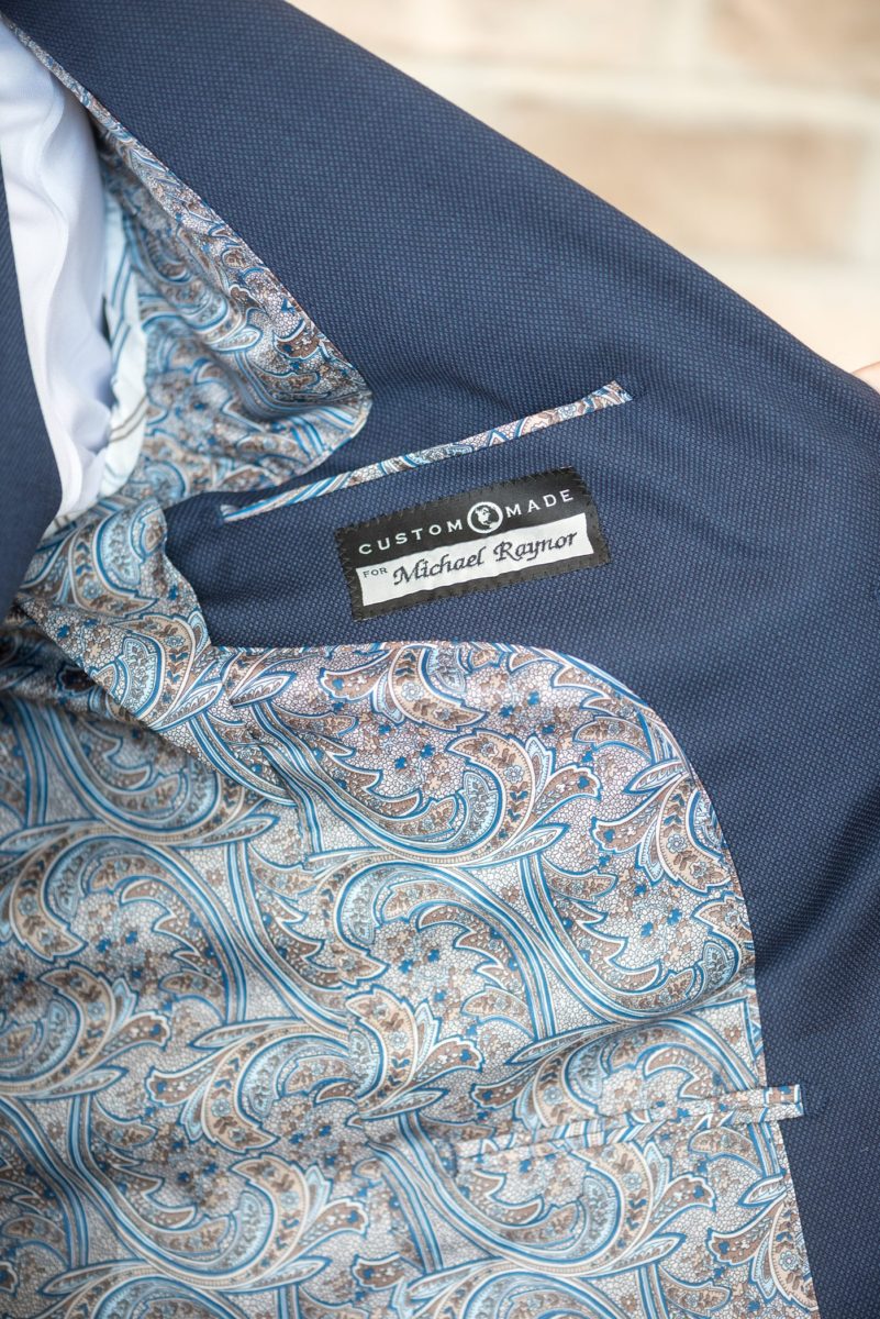 Detail photo of the groom's custom embroidery inside his blue suit jacket at Chatham Station by Mikkel Paige Photography. This beautiful Cary, North Carolina venue has indoor and outdoor spaces. #mikkelpaige #RaleighWeddingPhotographer #NorthCarolinaWeddings #SouthernWeddings #groomstyle #customsuit #weddingdetails