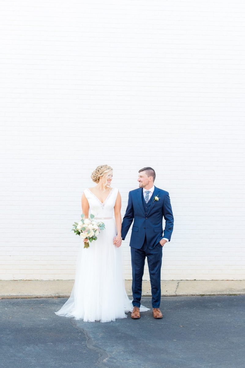 Chatham Station wedding photos by Mikkel Paige Photography from this urban chic beautiful venue in Cary, North Carolina. The bride wore a white tulle v-neck gown and up hair-do with braids and groom a blue suit with custom details for a fall celebration. #mikkelpaige #RaleighWeddingPhotographer #NorthCarolinaWeddings #SouthernWeddings #bridestyle #brideandgroom