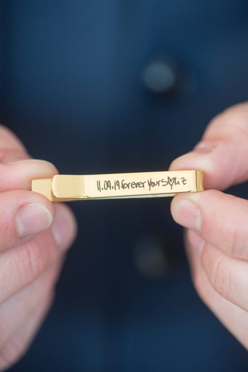 Detail photo of a tie clip the bride gifted the groom at Chatham Station by Mikkel Paige Photography. This beautiful Cary, North Carolina venue has indoor and outdoor spaces. #mikkelpaige #RaleighWeddingPhotographer #NorthCarolinaWeddings #SouthernWeddings #groomstyle #weddinggifts #tieclip