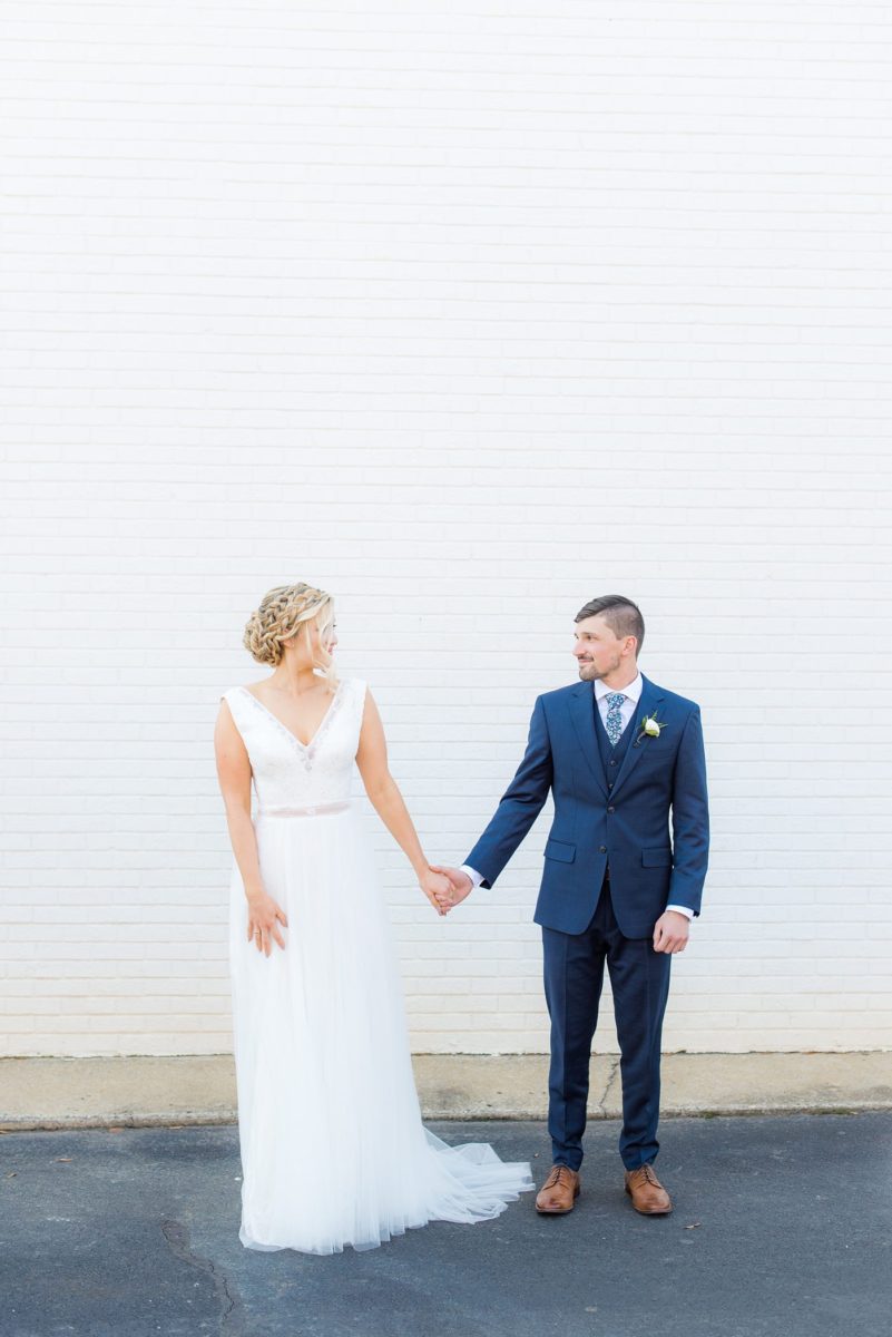 Chatham Station wedding photos by Mikkel Paige Photography from this urban chic beautiful venue in Cary, North Carolina. The bride wore a white tulle v-neck gown and up hair-do with braids and groom a blue suit with custom details for a fall celebration. #mikkelpaige #RaleighWeddingPhotographer #NorthCarolinaWeddings #SouthernWeddings #bridestyle #brideandgroom