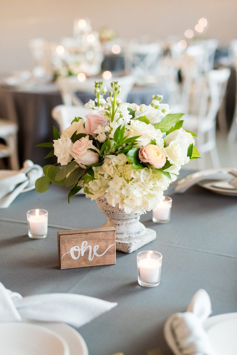 Fall photos at Cary, North Carolina wedding venue Chatham Station by Mikkel Paige Photography. The reception was filled with round tables, white cross-back chairs, grey linens, floral centerpieces and gold flatware. Candlelight filled the room and there were couches and velvet pillows for lounge areas. #mikkelpaige #RaleighWeddingPhotographer #NorthCarolinaWeddings #SouthernWeddings #fallwedding #RaleighWedding #CaryNorthCarolina #weddinglounge #weddingreception #greyandpinkwedding