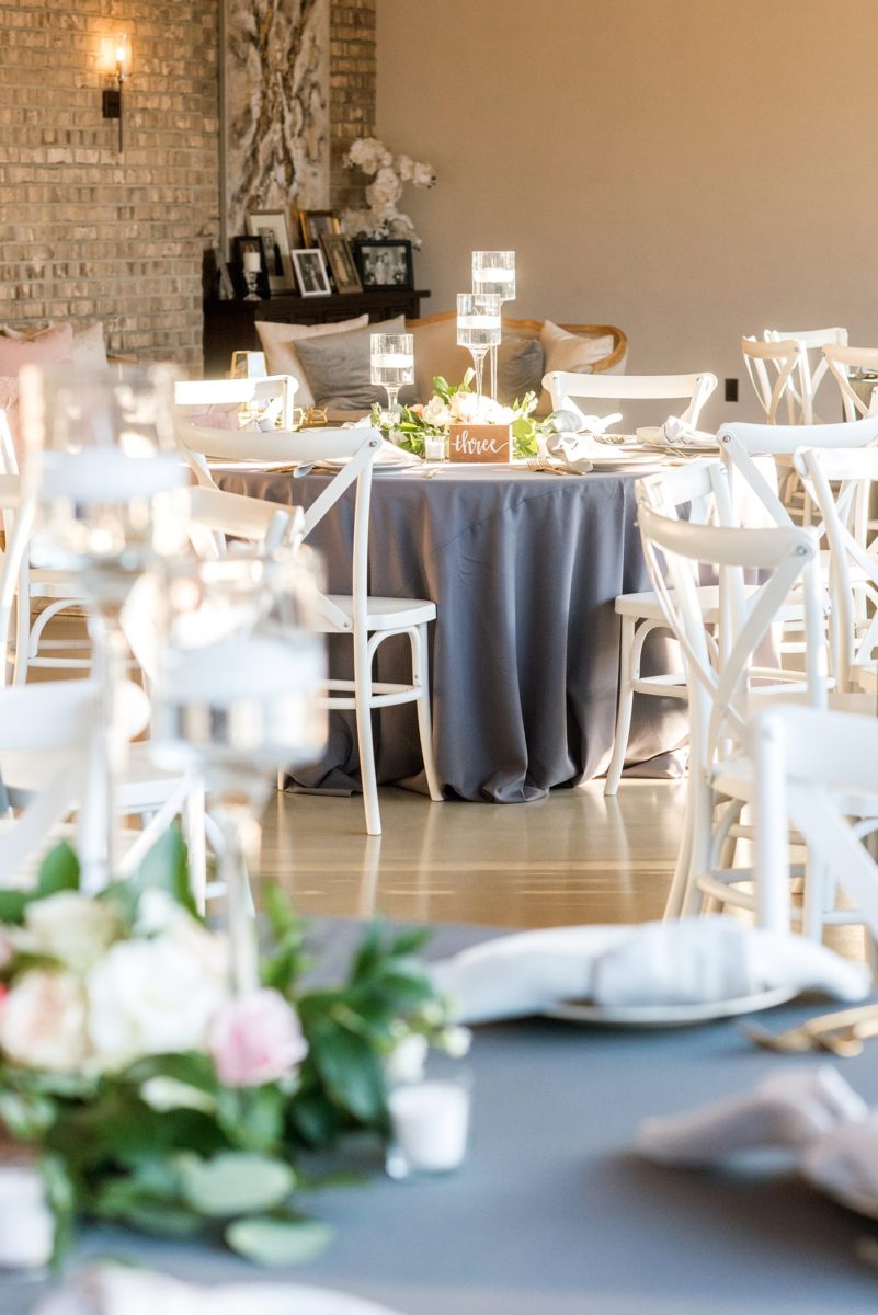 Fall photos at Cary, North Carolina wedding venue Chatham Station by Mikkel Paige Photography. The reception was filled with round tables, white cross-back chairs, grey linens, floral centerpieces and gold flatware. Candlelight filled the room and there were couches and velvet pillows for lounge areas. #mikkelpaige #RaleighWeddingPhotographer #NorthCarolinaWeddings #SouthernWeddings #fallwedding #RaleighWedding #CaryNorthCarolina #weddinglounge #weddingreception #greyandpinkwedding