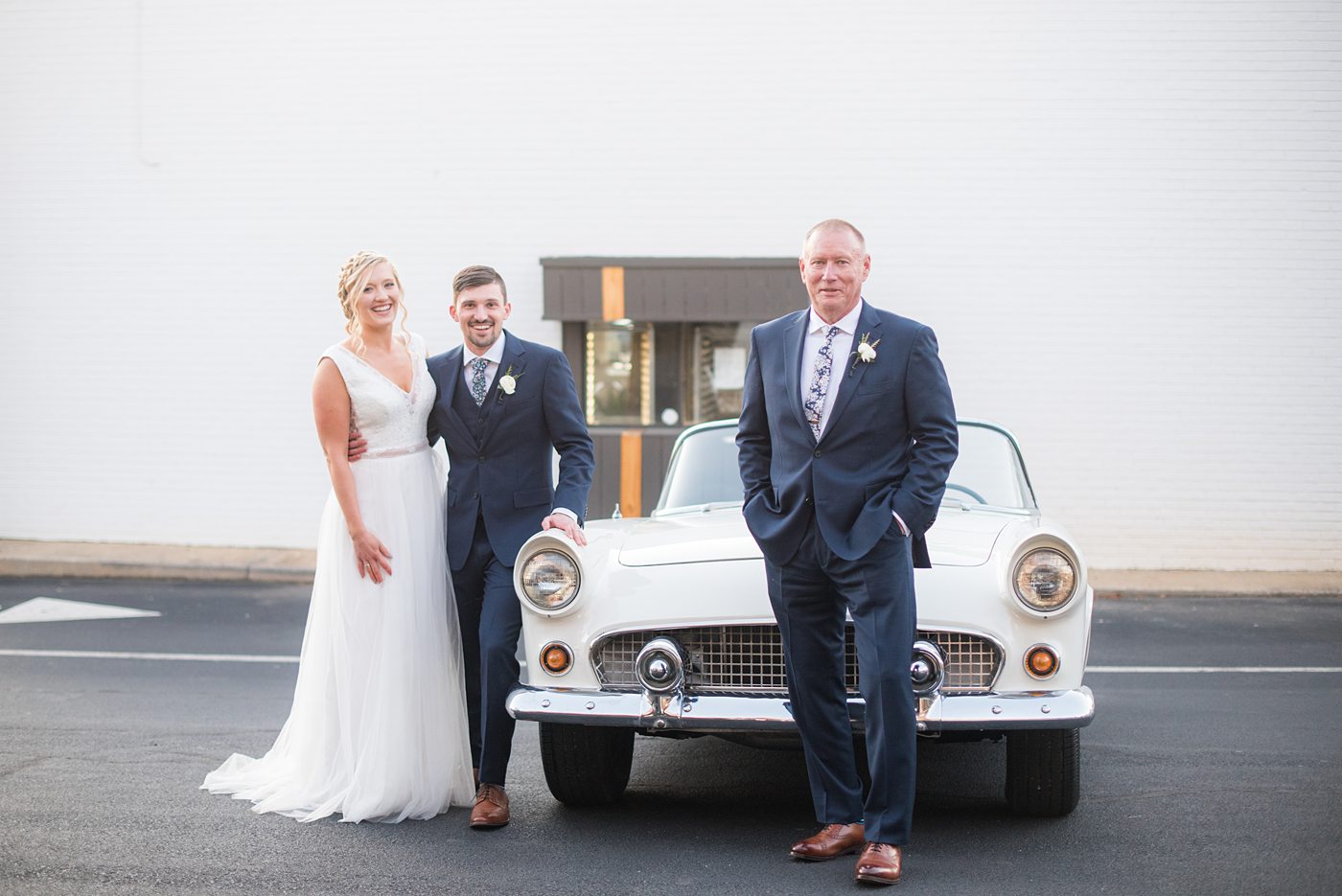 Chatham Station wedding photos by Mikkel Paige Photography from this urban chic beautiful venue in Cary, North Carolina. The bride wore a tulle v-neck gown and up hair-do with braids and groom a blue suit with custom details for a fall celebration. They took iconic photos with a vintage white Thunderbird car. #mikkelpaige #RaleighWeddingPhotographer #NorthCarolinaWeddings #SouthernWeddings #bridestyle #brideandgroom #vintagecar