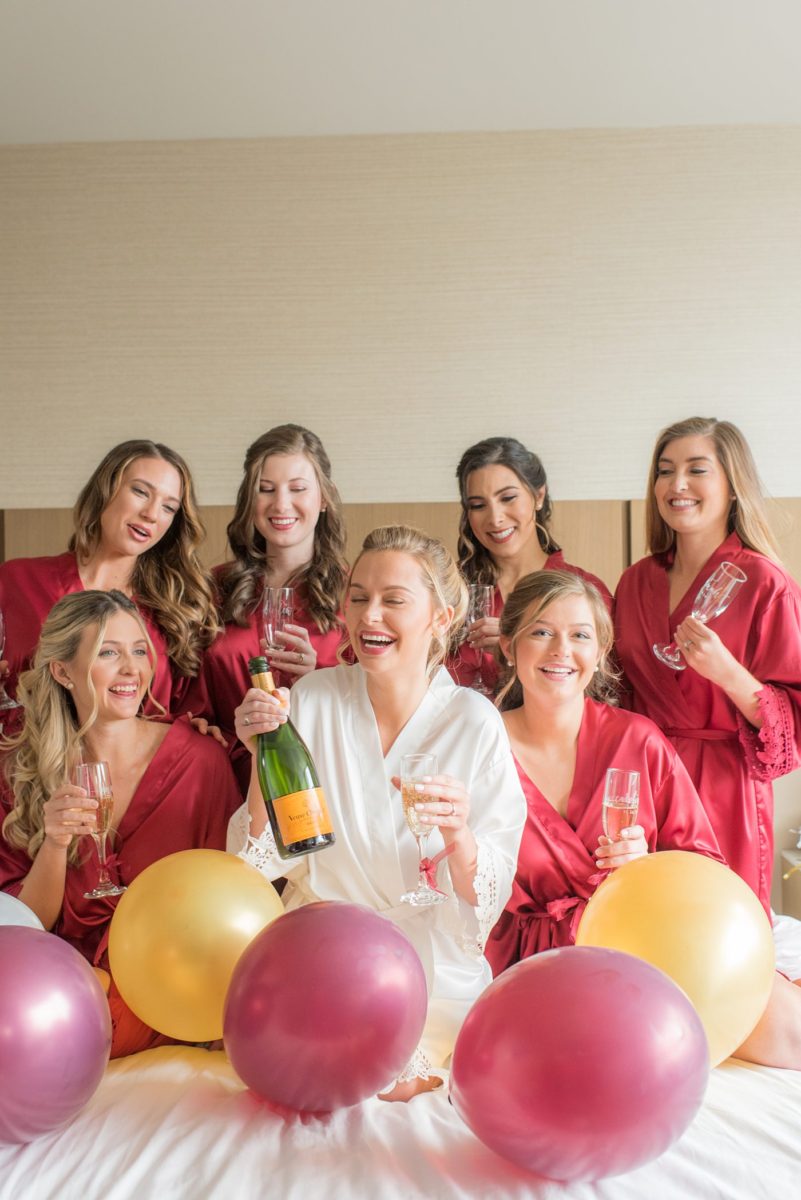 Wedding photographer Mikkel Paige Photography captures a ceremony at Duke Chapel and reception at The Rickhouse, a beautiful downtown venue in Durham, North Carolina. The bride got ready at the JB Duke Hotel with her bridesmaids in red silk robes. #durhamweddingphotographer #DukeChapelWedding #DurhamWeddingNorthCarolina #DurhamWeddingPhotographer #MikkelPaige #bridestyle #gettingready #champagnebride