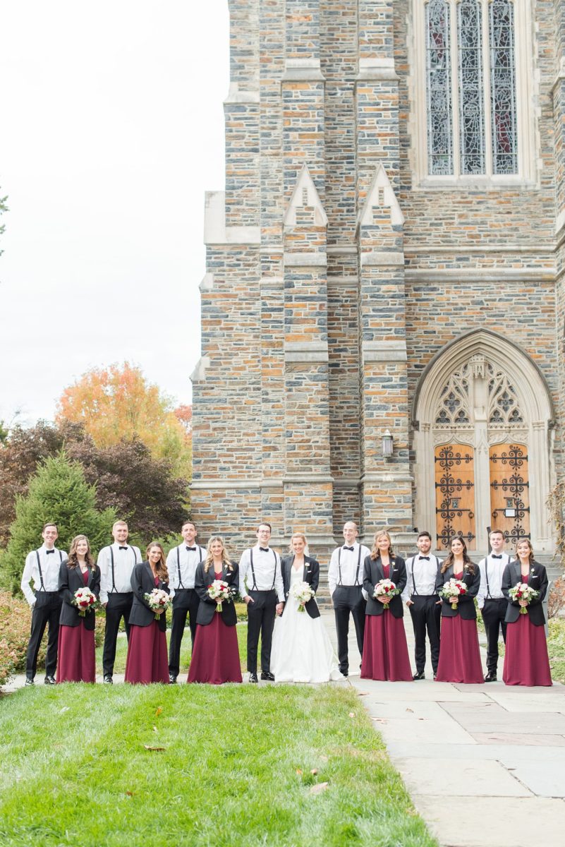 Wedding photographer Mikkel Paige Photography captures a ceremony at Duke Chapel and reception at The Rickhouse, a beautiful downtown venue in Durham, North Carolina. The bridesmaids wore maroon red, chiffon dresses and bride a v-neck white silk dupioni gown. The groomsmen, in classic black tuxedos, loaned the bridesmaids their coats to stay warm during the windy fall wedding. #DukeChapelWedding #DurhamWeddingNorthCarolina #DurhamWeddingPhotographer #MikkelPaige #bridalparty #maroonwedding