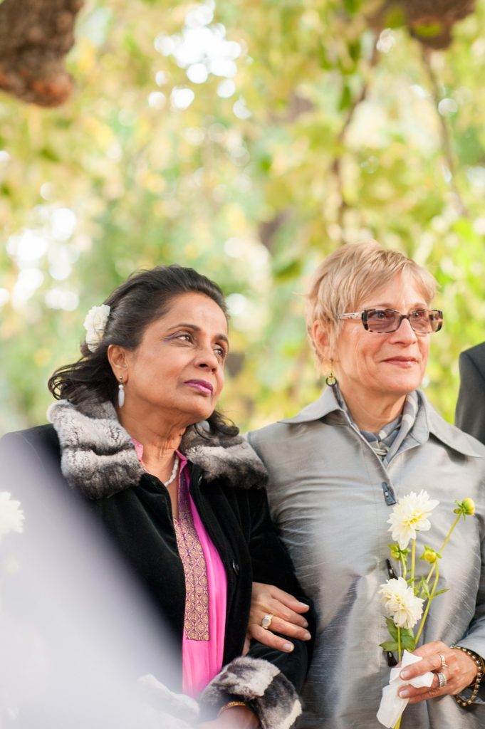 Mothers of the bride and groom look on during a small Brooklyn wedding elopement in NYC during Fall. Photos by Mikkel Paige Photography with a ceremony held at Fort Greene Park.