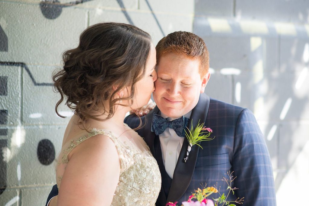 A 501 Union wedding in Brooklyn with photos by Mikkel Paige Photography. Two brides show affection during their same sex wedding day celebration.