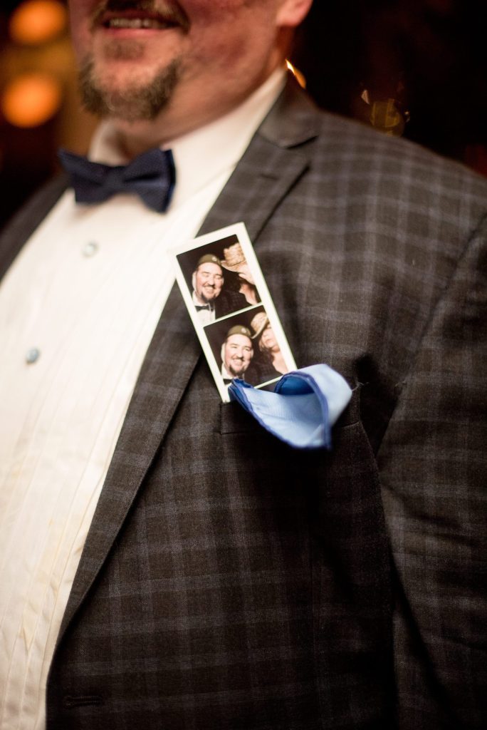 A picture of a guest with a photo booth strip from the brides' reception in Brooklyn. Photos by Mikkel Paige Photography.