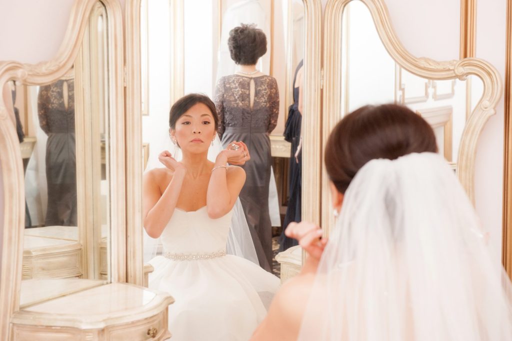 The bride applies perfume as a final touch before her first look at her Crystal Plaza Wedding in New Jersey with photos by Mikkel Paige Photography.