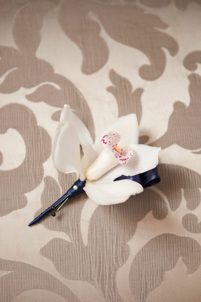 A photo of the groom's cymbidium orchid boutonniere by Mikkel Paige Photography at a luxury Crystal Plaza Wedding in New Jersey.