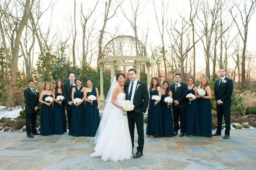 A photo of the bridal party in navy blue and black suits for a January wedding at the Crystal Plaza in NJ. Photos by Mikkel Paige Photography.