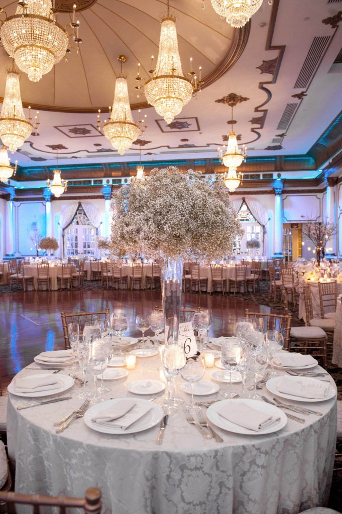 The reception room was covered in Baby's Breath centerpieces alternated with willow branches and orchids during a winter reception for a wedding at the Crystal Plaza in NJ. Photos by Mikkel Paige Photography.