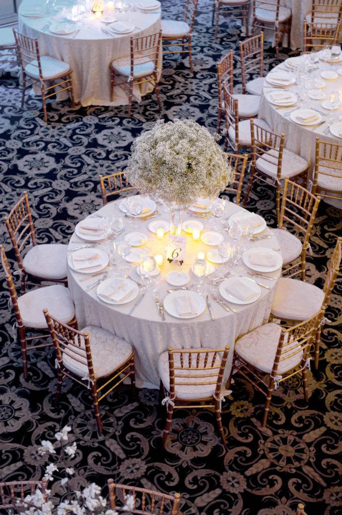 The reception room was covered in Baby's Breath centerpieces alternated with willow branches and orchids during a winter reception for a wedding at the Crystal Plaza in NJ. Photos by Mikkel Paige Photography.