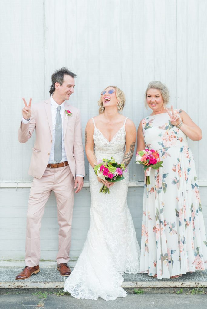 Fuquay-Varina wedding at Highgrove Estate in North Carolina with photos by Mikkel Paige Photography. The bride carried a tropical bouquet by Flowers on Broad Street. The fun bridal party photo had a bridesdude in a pink suit and bridesmaid in a floral gown.
