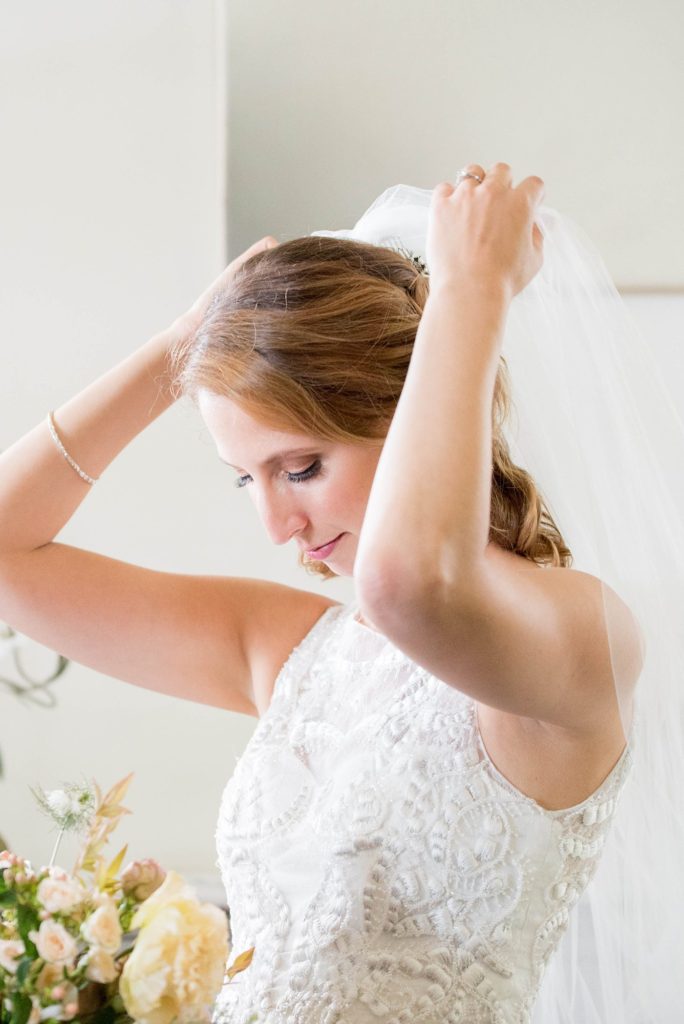 The bride puts on her veil at her marriage celebration at Southwood Estate. This Hudson Valley wedding was photographed by Mikkel Paige Photography and planned by The Union Studio.