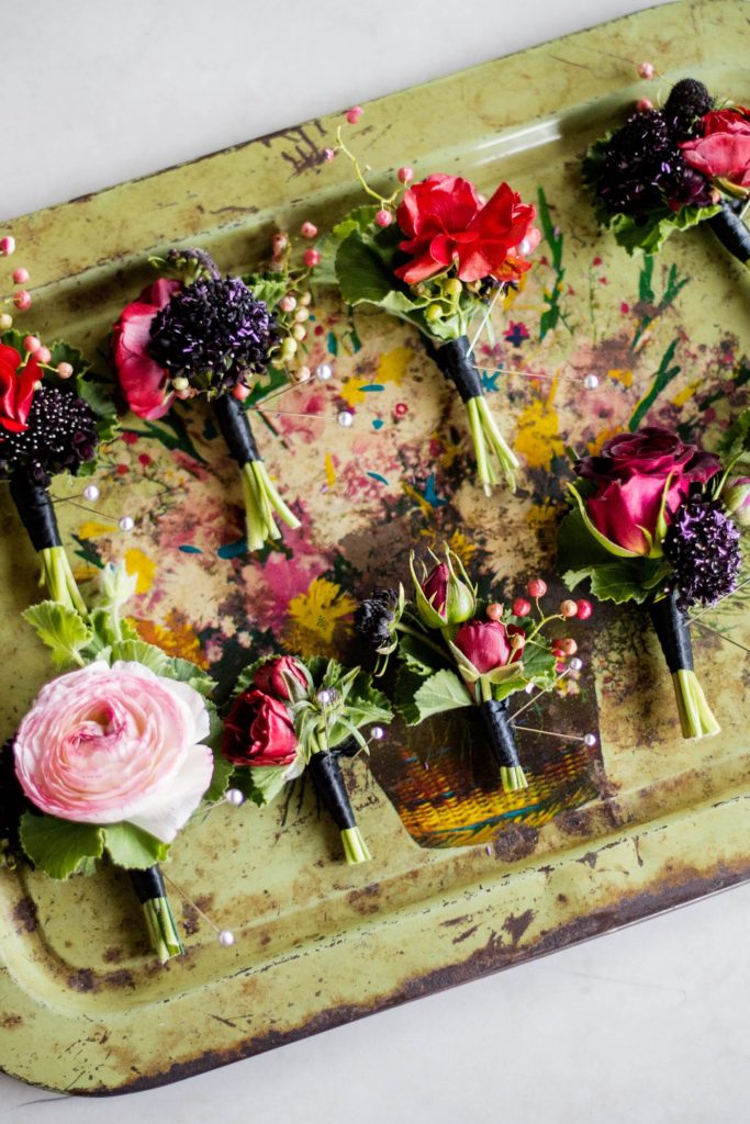 Photo of the boutonnieres in berry colors by Sachi Rose Designs. Image by Mikkel Paige Photography at a W Hoboken wedding.