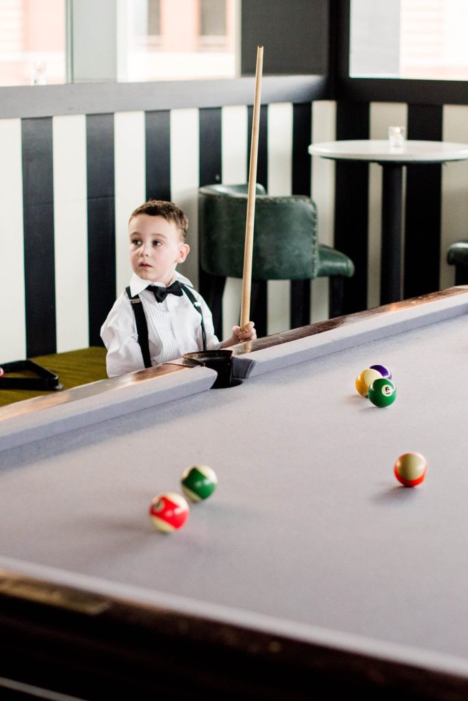 Photos of a ring bearer playing pool during a W Hoboken wedding, captured by Mikkel Paige Photography.